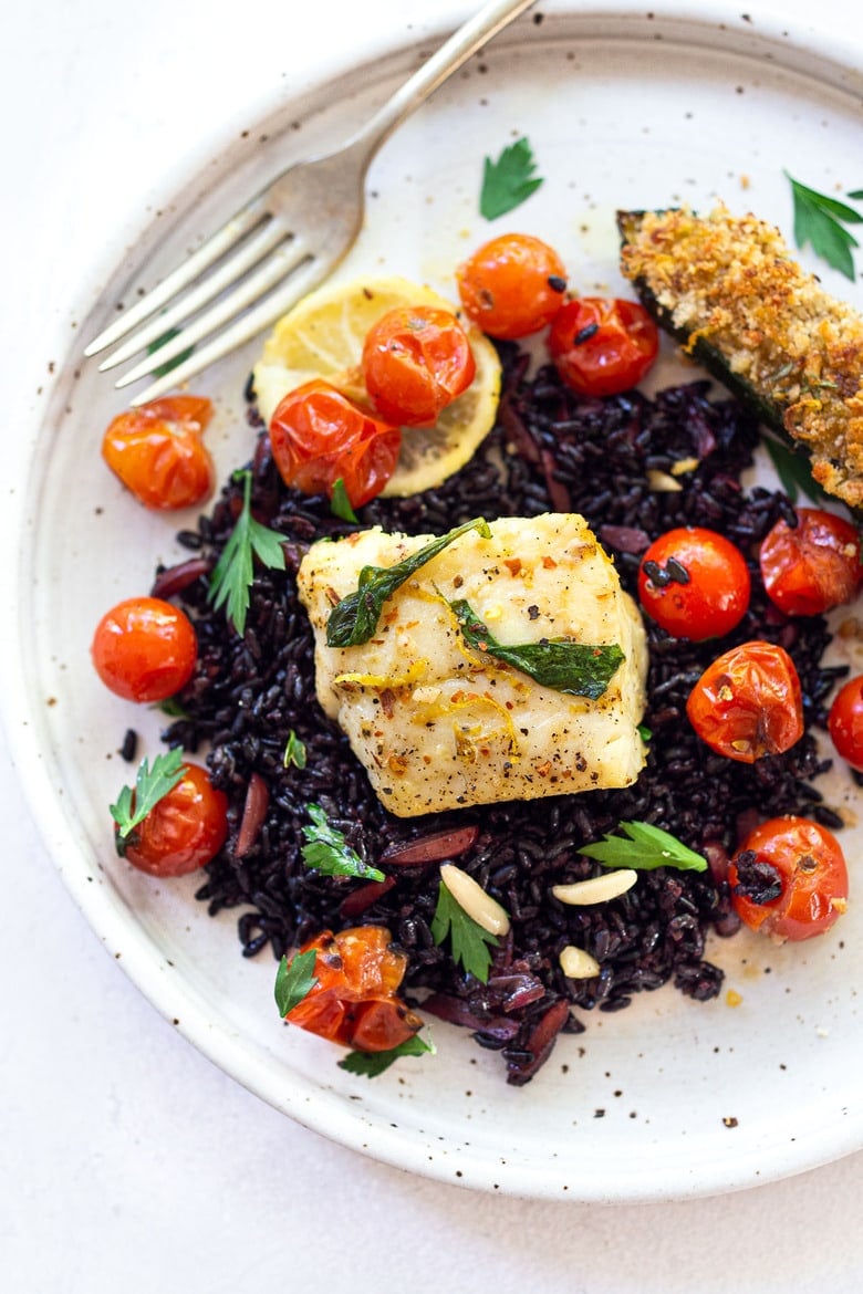 baked cod with burst tomatoes over black rice with baked zucchini.