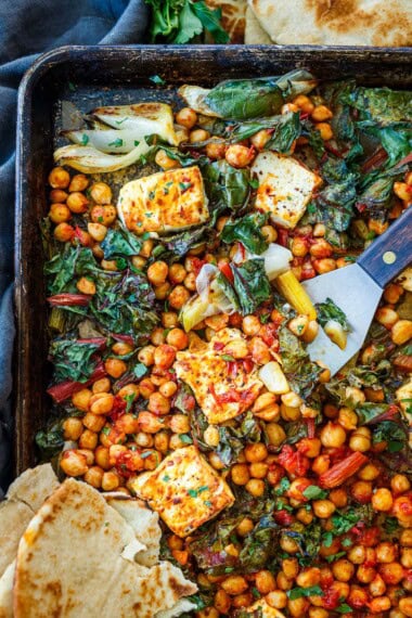 This baked feta with harissa chickpeas is a quick, bold sheet pan dinner packed with Mediterranean flavor. Serve as a main or a vibrant appetizer.