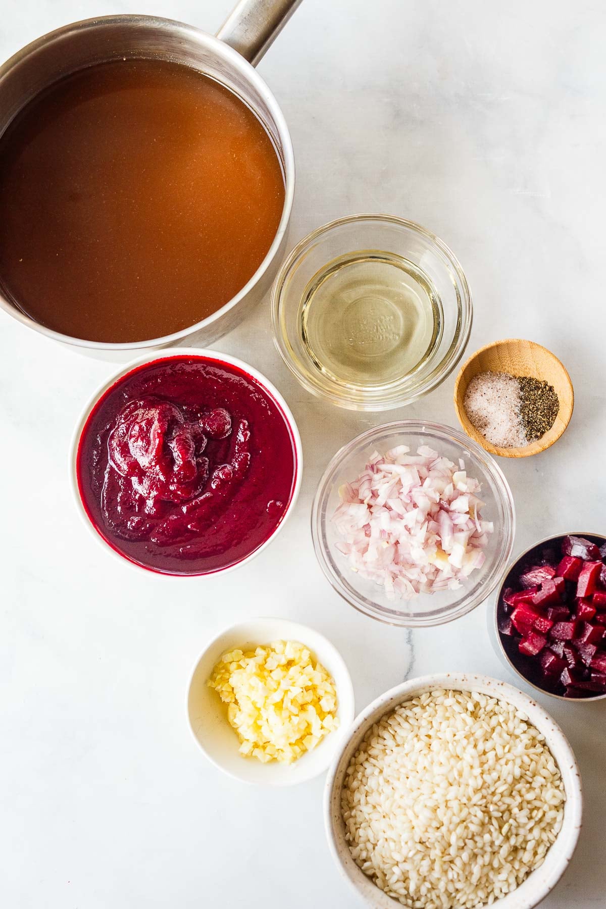 all components to make beet risotto - pot of warm broth and small dishes of beet purée, wine, salt and pepper, diced shallots and minced garlic, diced beets, and arborio rice.