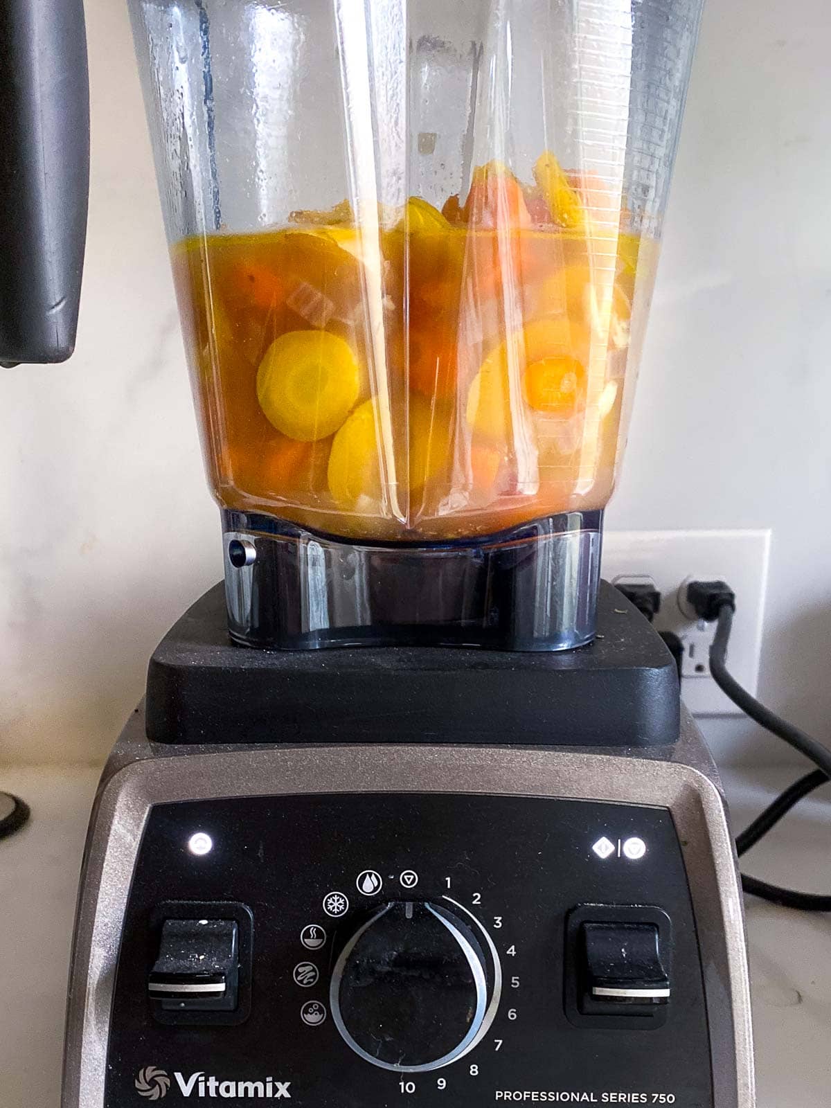 blending the carrot soup in a blender.