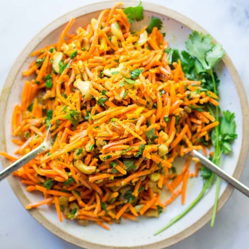 Fresh and flavorful, this carrot salad recipe is infused with Indian flavor! Studded with toasted cashews and raisins, fresh grated carrots are tossed in a delicious Indian curry dressing. Easy, healthy, vegan, and perfect for gatherings!