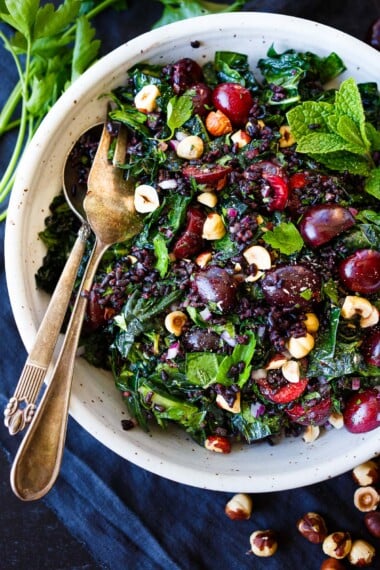 This refreshing cherry salad recipe features lacinato kale, black rice, fresh mint, toasted hazelnuts, and creamy goat cheese in a tangy red wine vinaigrette. It is vegan-adaptable.