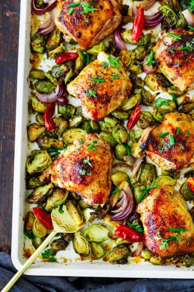marinated szechuan sheet pan chicken with brussels sprouts and red onion and red chilies.