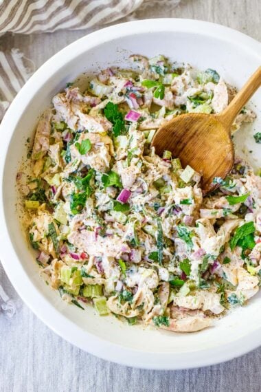 the best chicken salad salad recipe in a white bowl with a wood spoon.