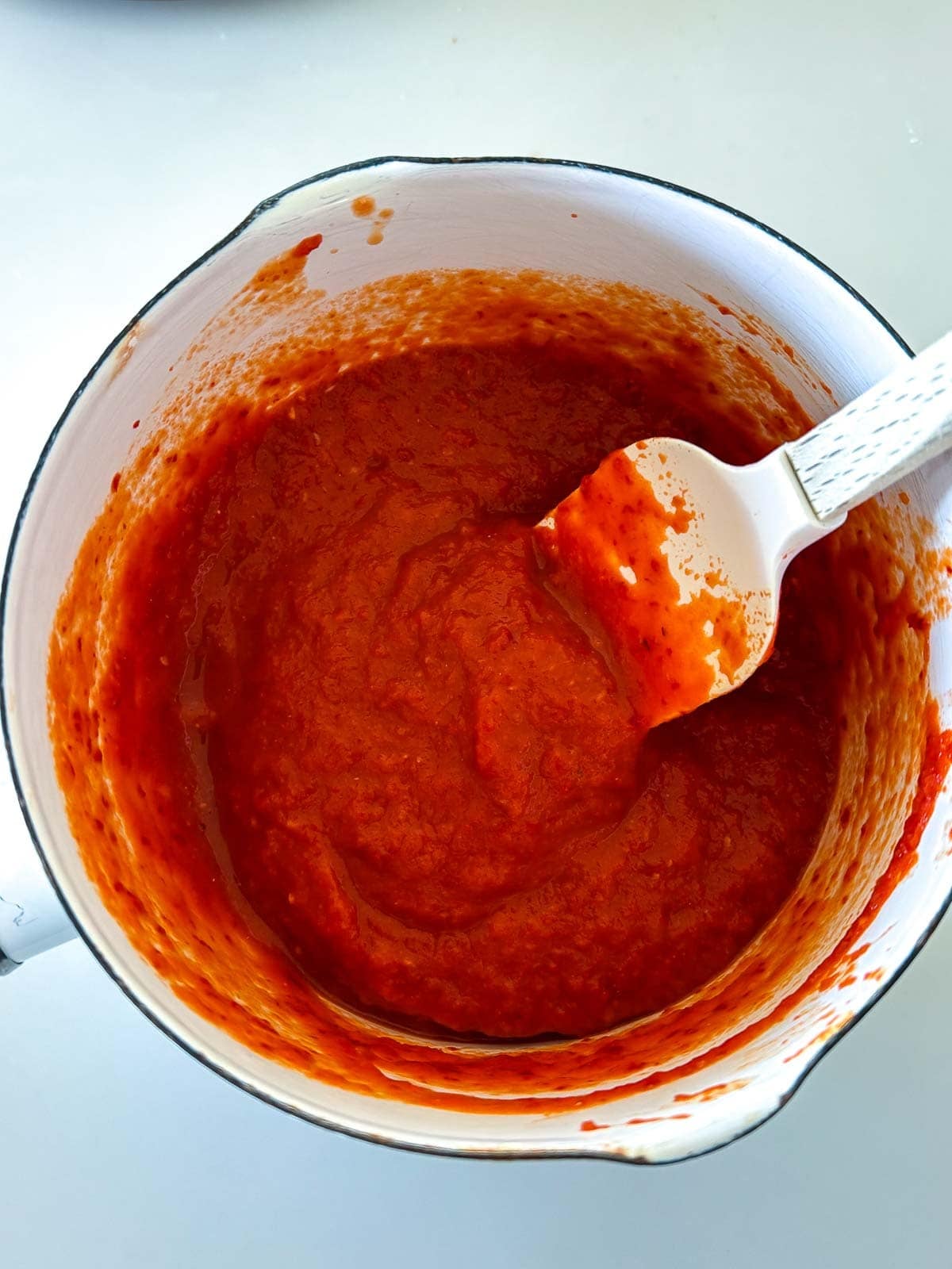 small saucepan with spatula stirring chili garlic sauce.