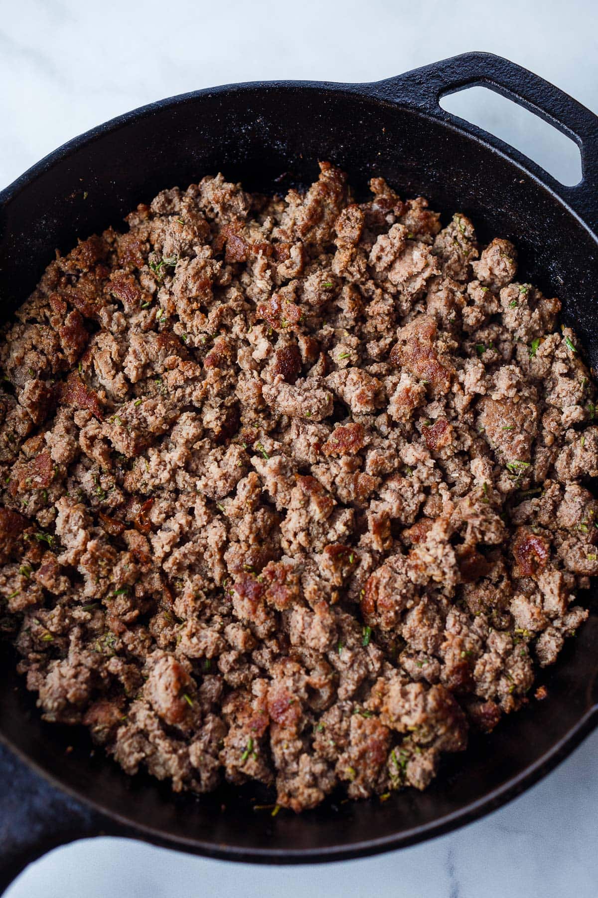 ground beef browning in cast iron skillet. 