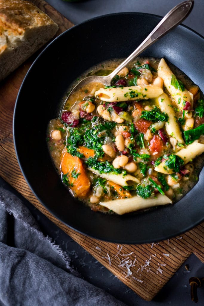 bowl of minestrone soup with noodles, kale, veggies, and beans. 