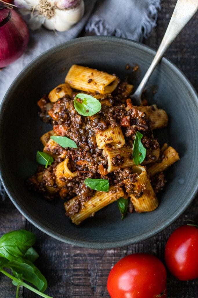 easy vegan recipe: lentil bolognese on noodles in a bowl garnished with basil.