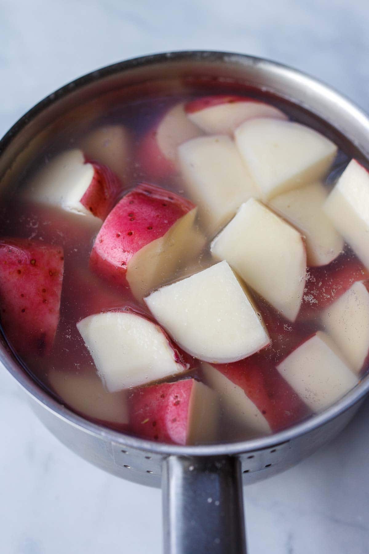 chopped red potatoes in pot with water.