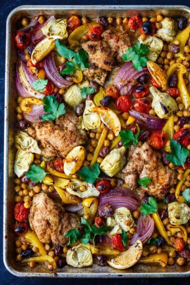 Mediterranean Chicken with veggies, chickpeas, olives and herbs. A delicious sheet pan dinner that is easy to make and easy to clean up! 