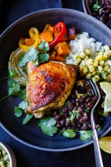 mojo chicken with cuban black beans, mango salsa, rice, roasted pepper and sweet potatoes, and fresh cilantro, a caribbean recipe.