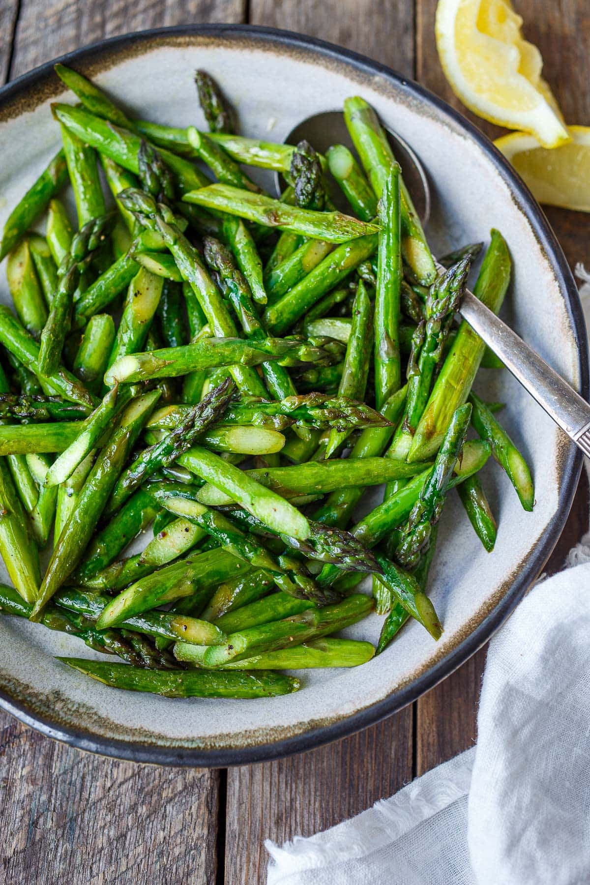 plate of sautéed asparagus with silver spoon. 