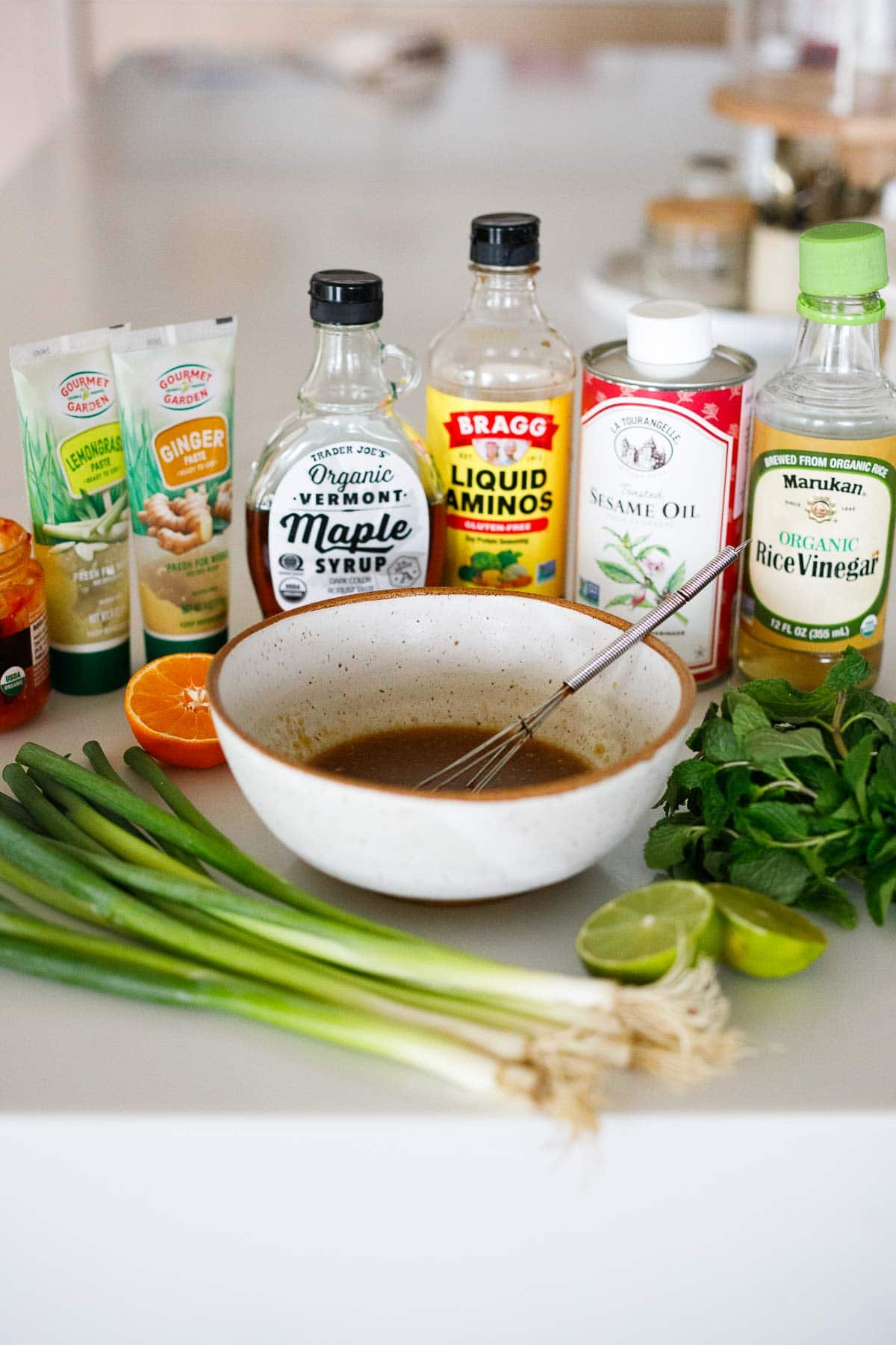 ingredients for thai dressing surrounding bowl of dressing with whisk. 