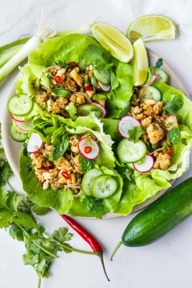 Thai tofu larb in butter lettuce wraps garnished with sliced cucumber and radish and chiles.