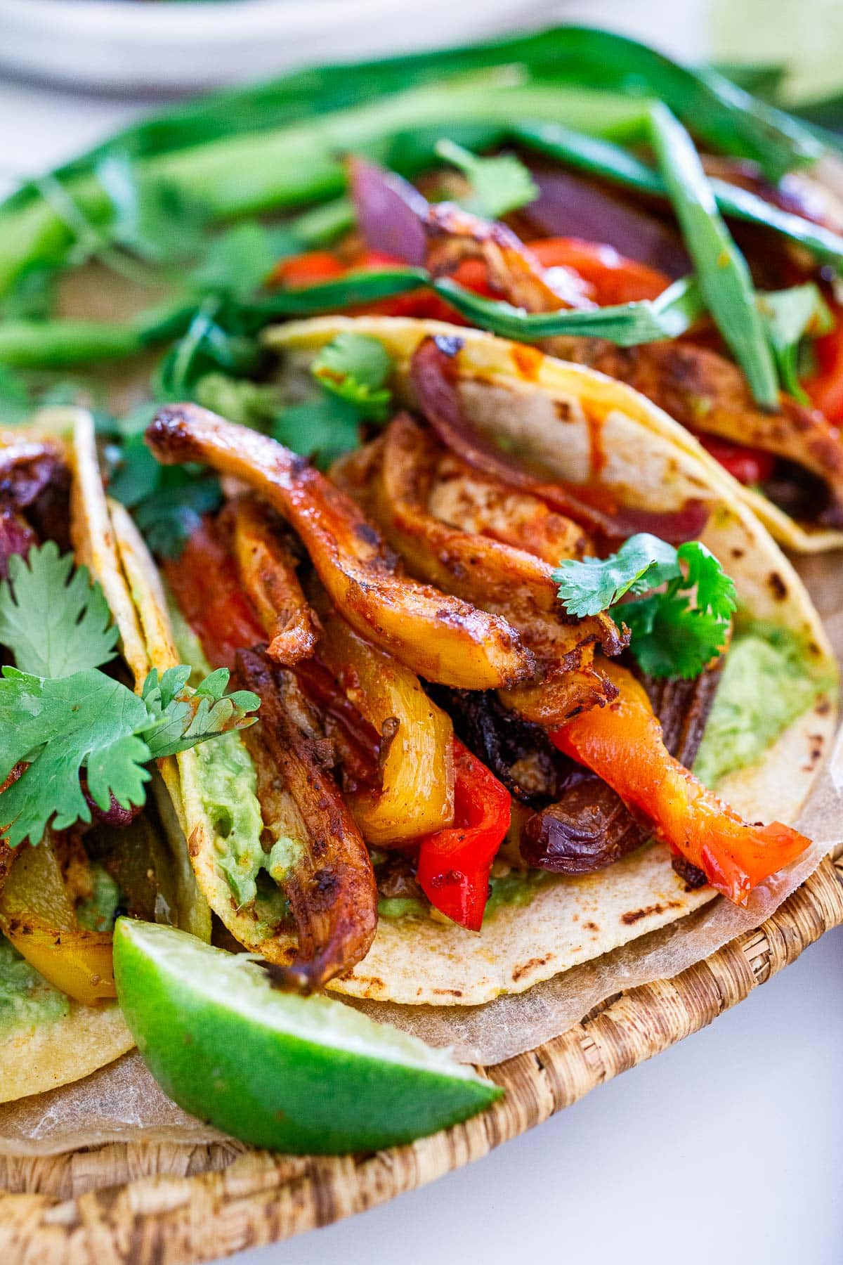 vegan fajitas with corn tortillas, fajita veggies, oyster mushrooms, and mashed avocado, topped with cilantro.