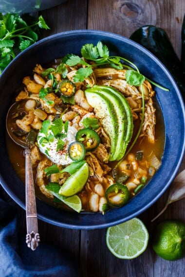 Cozy up with a bowl of White Bean Chicken Chili made with tender shredded chicken, poblano chilies, white beans, cilantro, coriander, and lime.  Flavorful and hearty, this one-pot meal is nourishing and delicious!